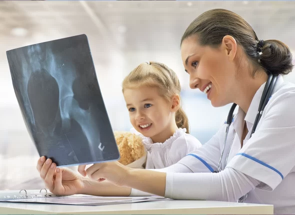 Rdaióloga mirando una radiografía junto a una niña